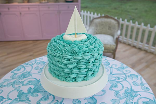 bolo redondo e azul, com um barquinho em cima, com chantili azul e recheio de leite em pó do dário