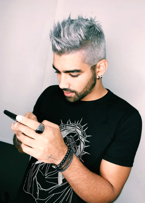 Com cabelo platinado, Dilsinho mexe no celular enquanto é fotografado