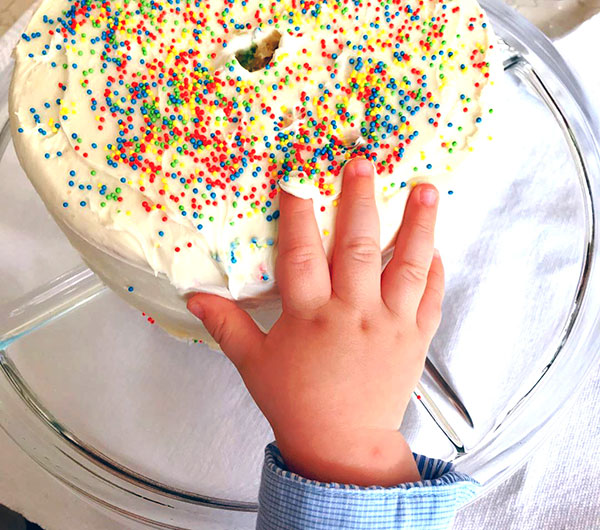 Filho de Anahi colocando a mão no bolo de aniversário