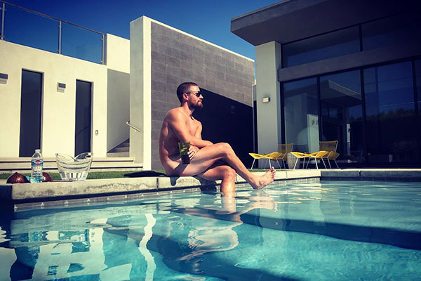 Stephen Amell sem sunga na beira de uma piscina