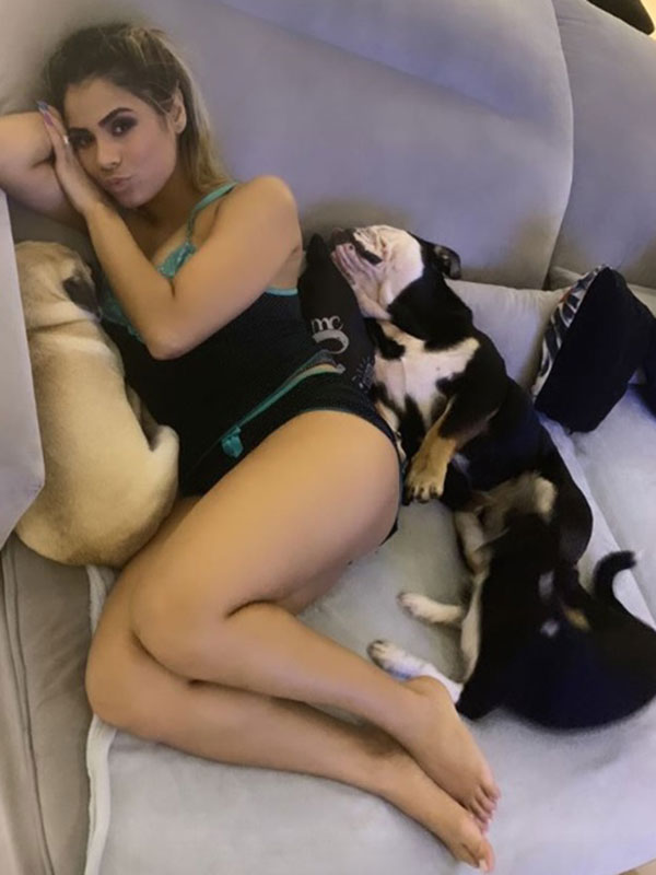 Lexa deitada com três cachorros em um sofá