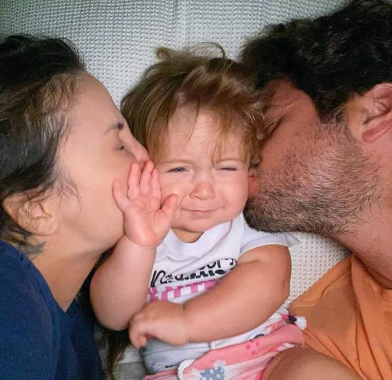 Bela sendo beijada por Claudia Leitte e Marcio Pedreira, seus pais