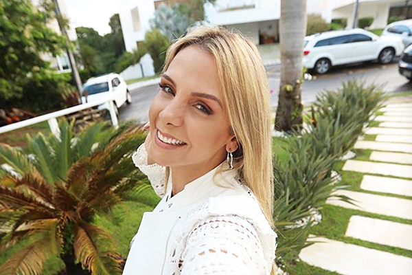 Com uma roupa branca, Carla Perez faz selfie no jardim de casa