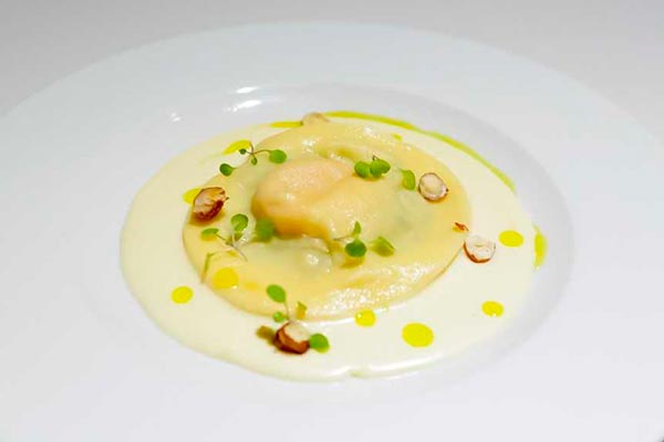Raviolo de gema com fonduta de parmesão e avelãs tostadas