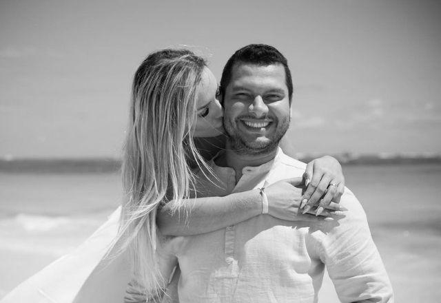 Foto em preto e branco mostra Andressa Urach e o marido abraçados, na praia