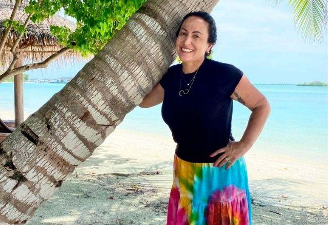 Simone Meina, abraçada em um coqueiro, na praia