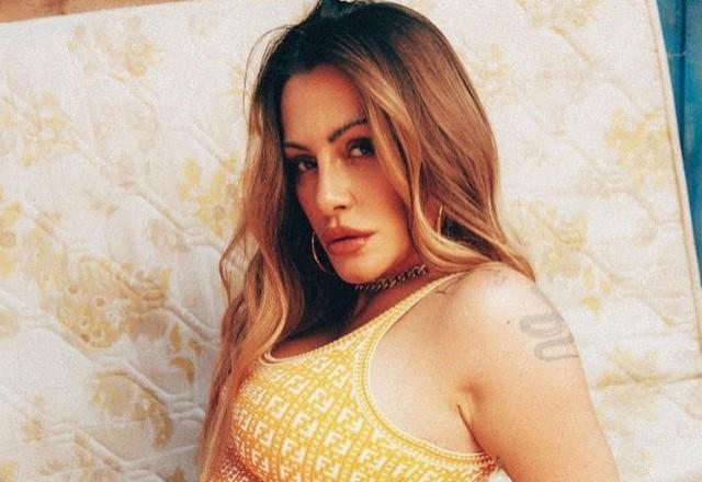 Cleo posa sensual de vestido justo sentada em colchão