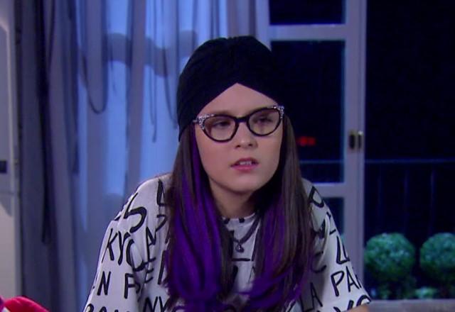 Isabela com turbante preto e uma expressão séria e desconfiada