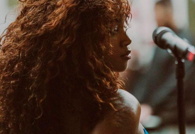 A cantora IZA posa de lado em palco