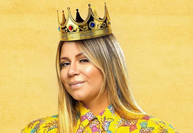Marília Mendonça posa em frente a fundo amarelo e usando coroa