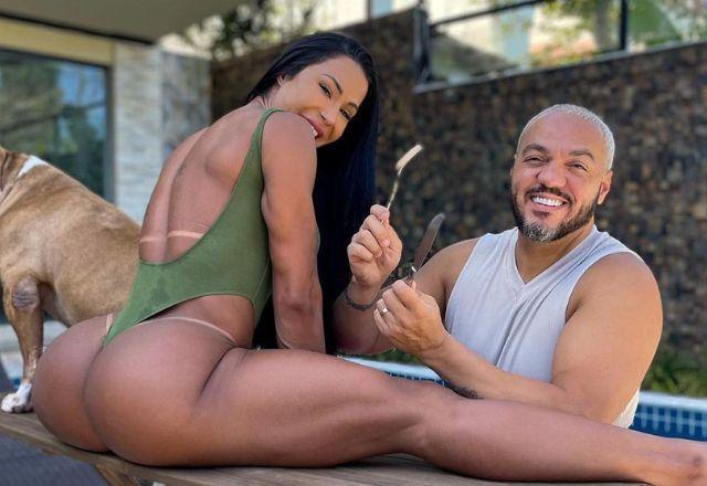 Gracyanne Barbosa abre espacate em cima da mesa, e Belo sorri ao lado