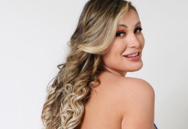 Andressa Urach posa de costas sorrindo e olhando para trás