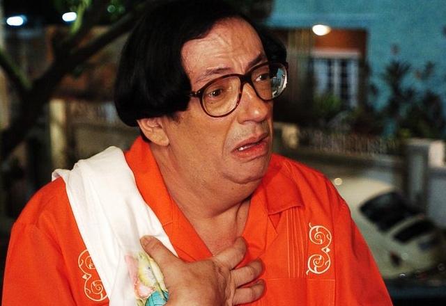 Foto de Marcos Oliveira, ator que interpreta Beiçola, vestido com uma roupa laranja e com expressão triste