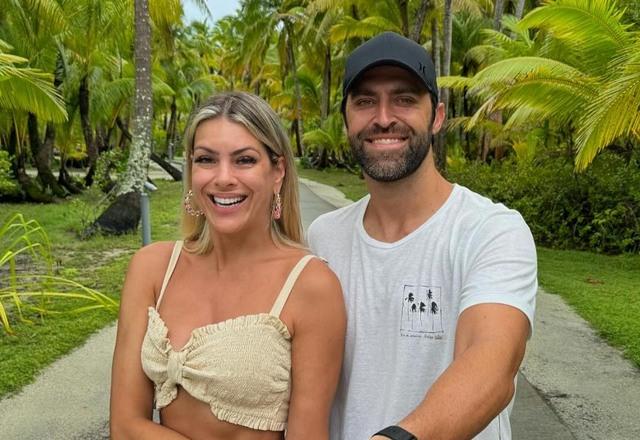 Foto de Renata Fan com seu namorado Átila Abreu, em uma paisagem verde, sorrindo para a foto