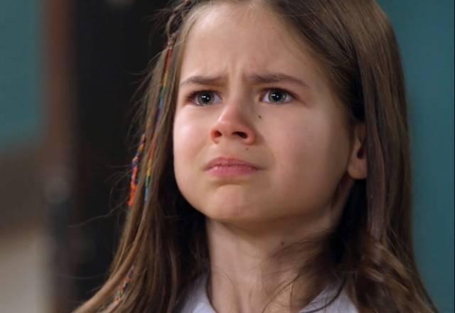 Anna olha com cara de choro para a diretora Norma