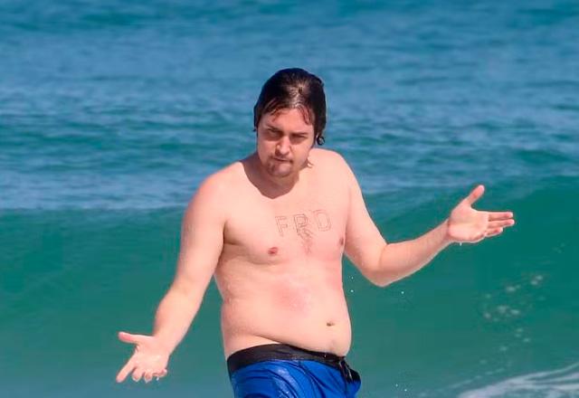 Felipe Dylon surfando em praia.