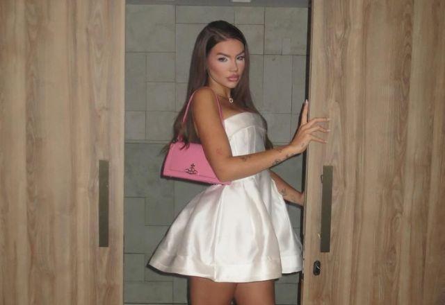 Vivi posa para foto com vestido branco e bolsa rosa.