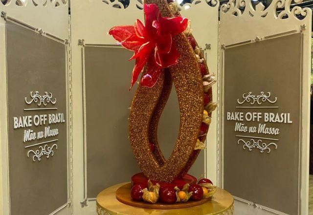 Na foto temos uma escultura de caramelo decorada com brigadeiros caramelizados, physalis, flor vermelha de papel arroz e detalhes dourados.