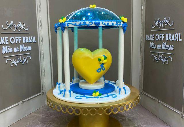 Na foto temos uma sobremesa inspirada na arquitetura siciliana, com coração de chocolate recheado com mousse, cúpula azul de isomalt, pilares de chocolate e decoração com limões.