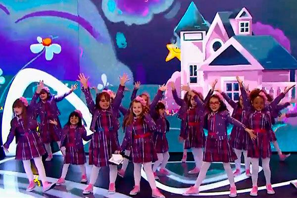 Crianças de Carinha de Anjo cantam no palco do Teleton