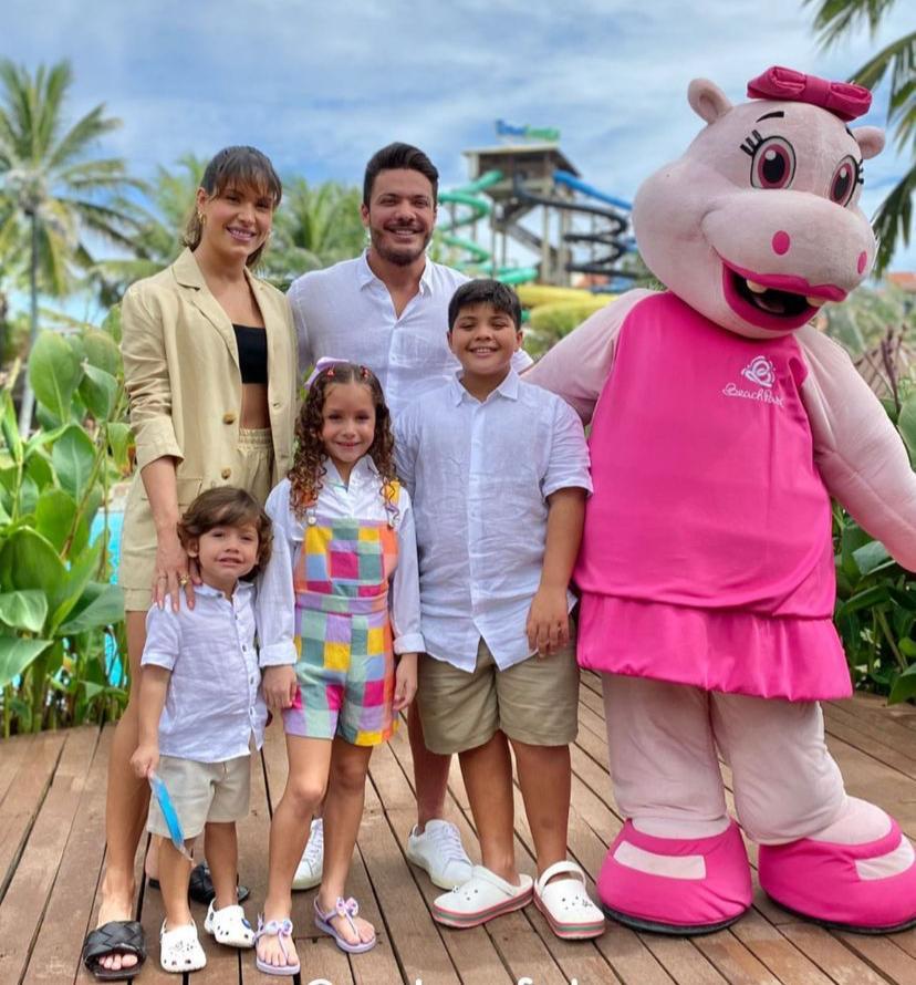 Família de Wesley Safadão reunida ao lado de um personagem infantil, em um parque aquático de fortaleza. Todos sorriam para a foto