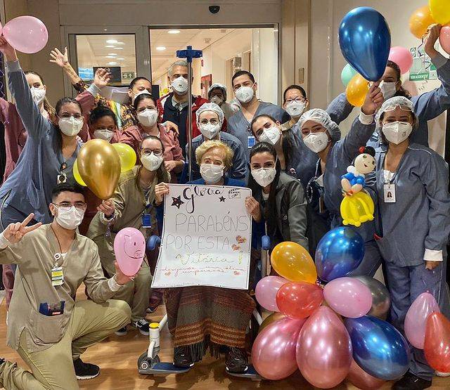 Glória Menezes posa ao lado de médicos e enfermeiros na saída de hospital