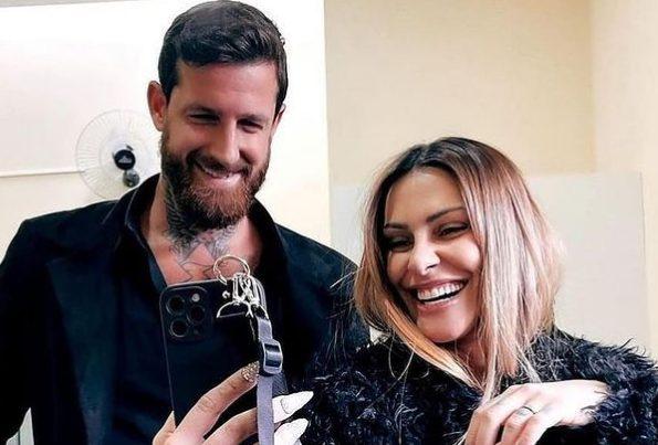 Cleo sorrindo para a câmera ao lado do marido.