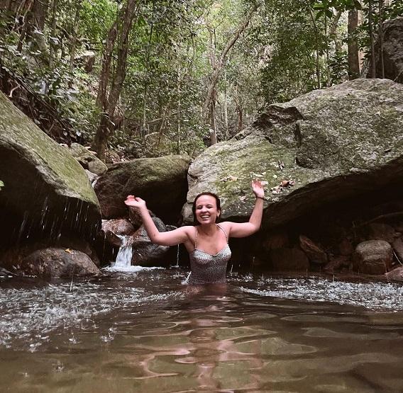 Larissa Manoela com os braços para cima dentro de um rio