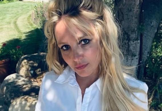 Britney Spears posa no jardim com uma camisa branca