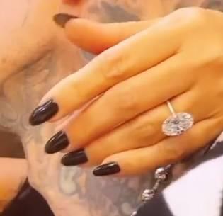 Mãos de Kourtney Kardashian com unhas pretas e anel com diamante grande oval