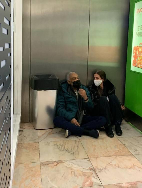 Gilberto Gil e Flora Gil sentados no chão do aeroporto