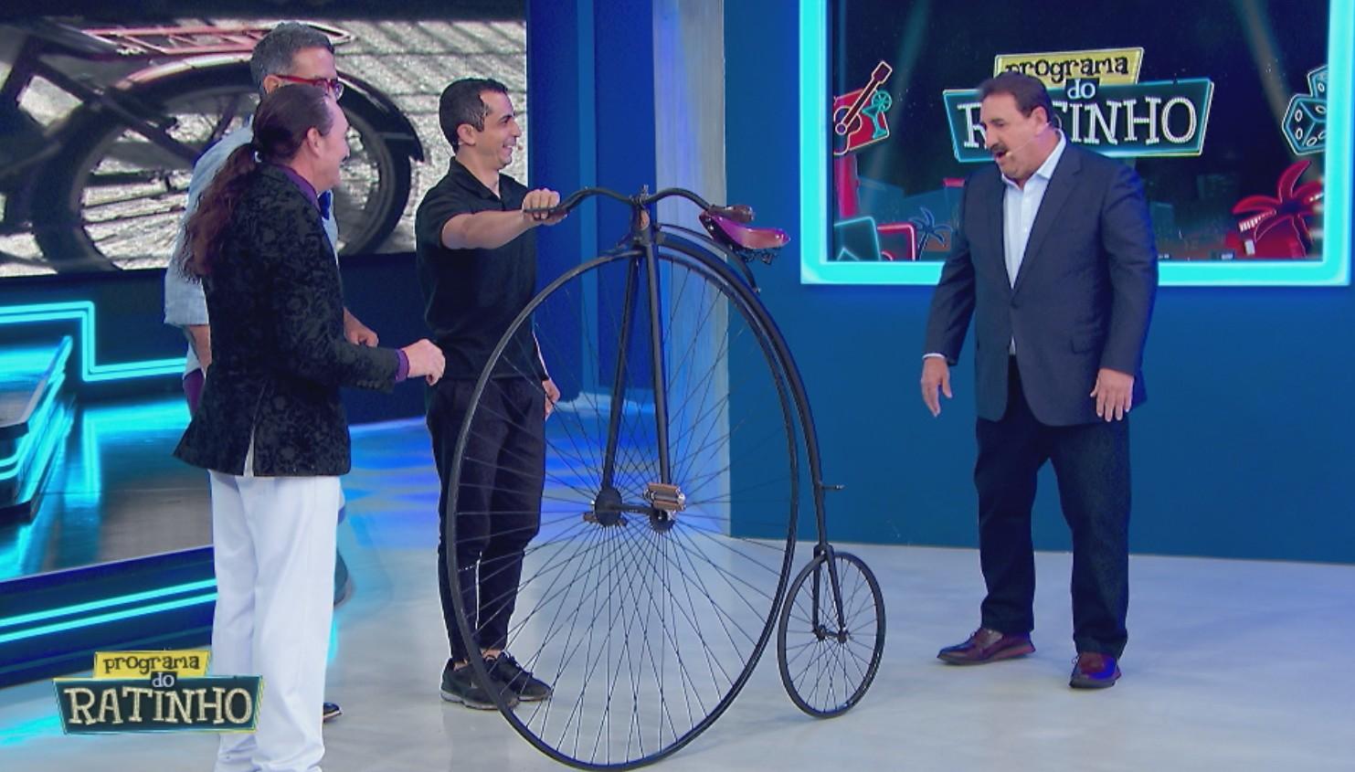 Ratinho e convidados conversando com uma bicicleta no palco.