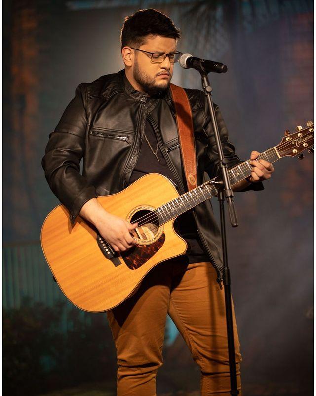 Maurílio tocando violão durante show 