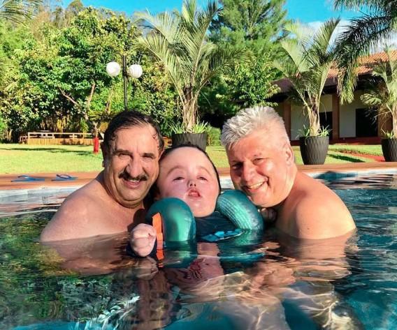 Ratinho posa sorrindo dentro da piscina ao lado do neto Noah 