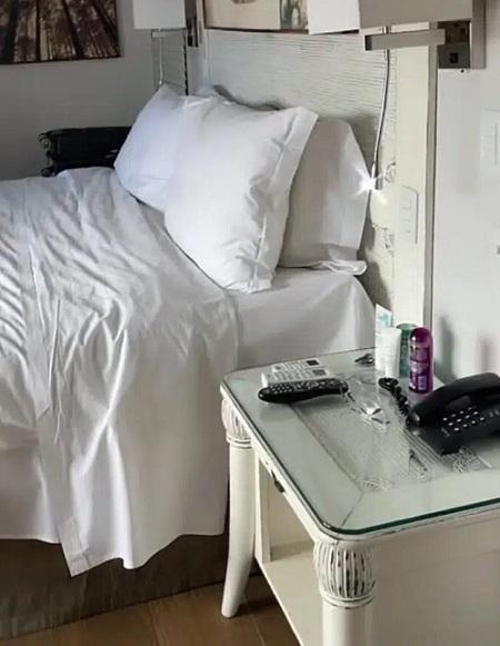 Cama e escrivaninha, ambas na cor branca, em um quarto de hotel