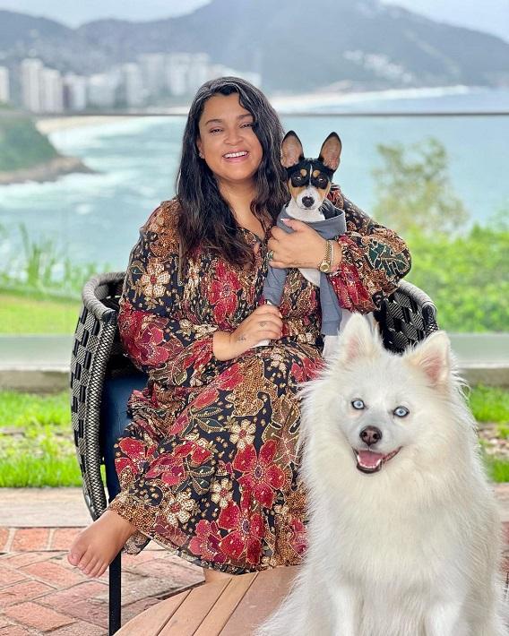 Preta Gil posa sentada com um de seus cachorros no colo