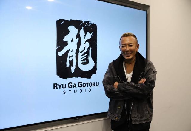 Foto de Toshihiro Nagoshi ao lado do logo do Ryu Ga Gotoku Studio