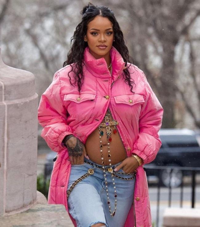 Rihanna aparece caminhando, com uma blusa na cor rosa e mostra a barriga.