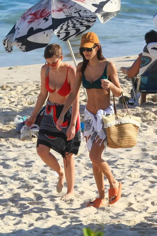 Vitória Strada e a noiva Marcella Rica durante passeio na praia.