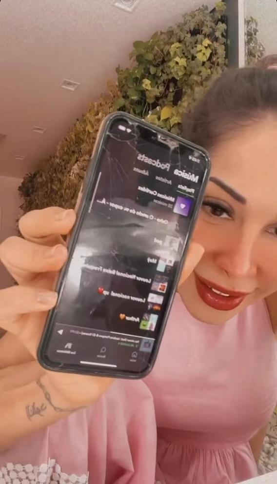 maira segura um celular para mostrar sua playlist de louvores