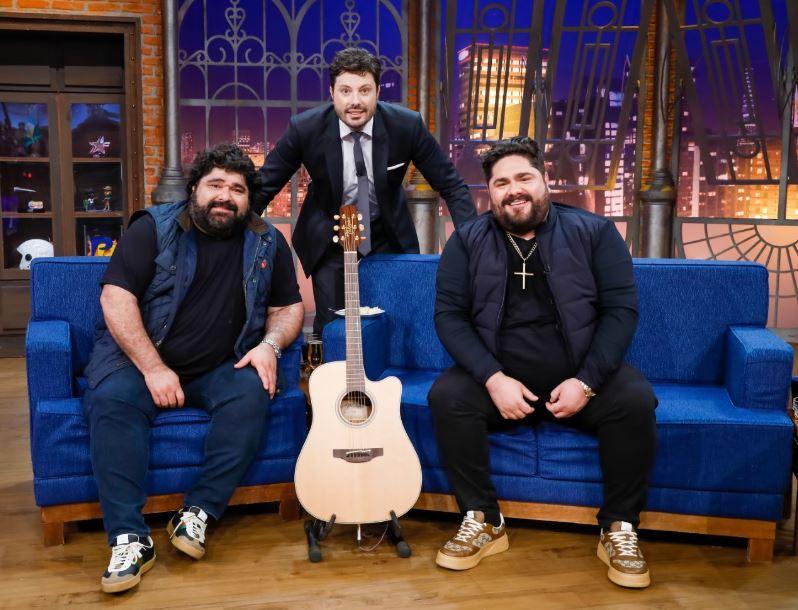 Danilo Gentili e César Menotti & Fabiano posam para foto no palco.