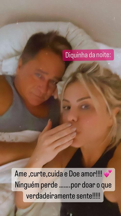 Poliana e Leonardo olham para a foto, deitados em meio a lençóis da cama