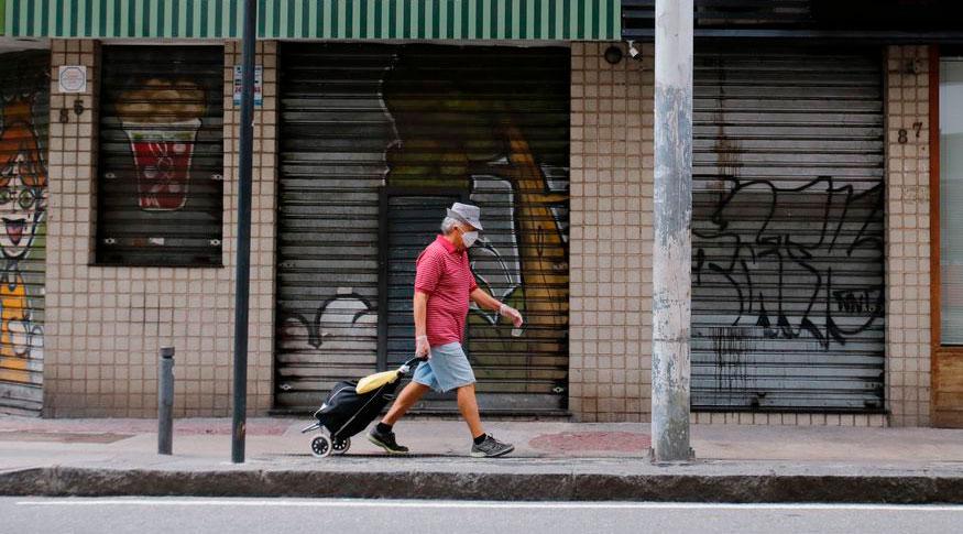 Idoso caminha em frente de comércios com as portas fechadas (Tânia Rêgo/Agência Brasil)