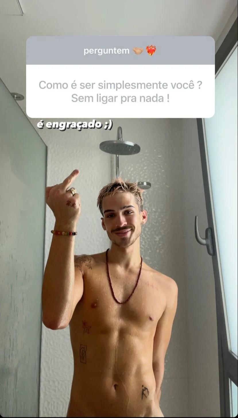 Dentro do box, com água correndo pelo corpo, João Guilherme posa e sorri para a foto