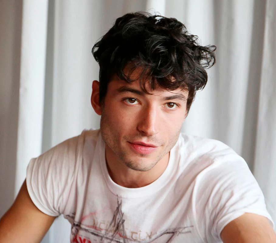 Ezra Miller veste uma camiseta branca e sorri