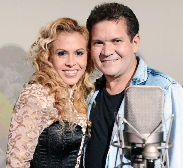 Joelma e Ximbinha sorriem para foto enquanto se abraçam. Um microfone é fotografado perto do ex-casal.