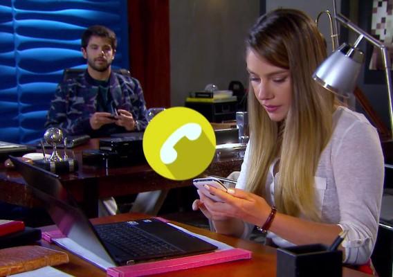 Rebeca aparece em primeiro plano, na mesa com um notebook e olhando para o celular que está na mão, Otávio aparece em segundo plano, olhando a cena