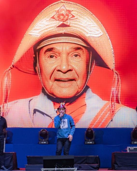 João Gomes em cima do palco cantando; atrás, uma imagem feita por meio de inteligência artificial de Luiz Gonzaga