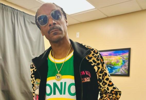 Snoop Dogg posa com cara séria, óculos escuros, camisa colorida e jaqueta com estampa de oncinha