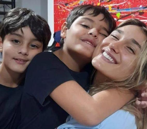 Sasha e irmãos posam abraçados e sorrindo